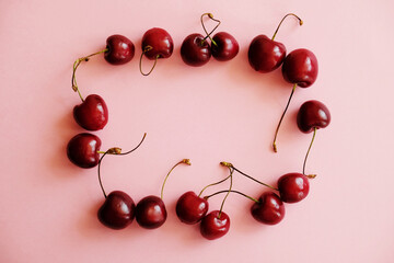 Obraz na płótnie Canvas Cherry frame. Flat lay of cherries on a soft pink background.