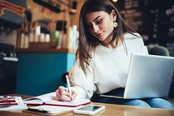 Focused woman with laptop taking notes