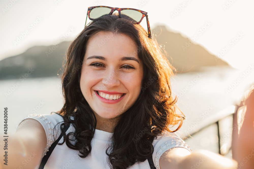 Wall mural Portrait with a point of view shot of a happy young woman by the sea at sunset