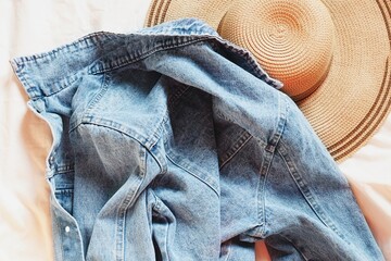 Sun hat and light blue denim jacket. Summer women's clothes flat lay photography. Casual outfit top view