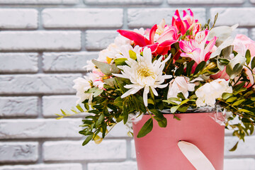 Delicate bouquet of different flowers in pink packaging. Square photo close-up