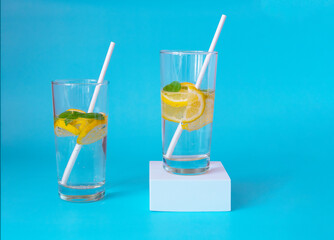 Lemonade on a blue background and a white podium. Refreshing summer drink with copy space