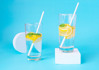 Lemonade on a blue background and a white podium. Refreshing summer drink with copy space