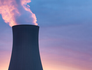 Nuclear power plant against sky at sunset