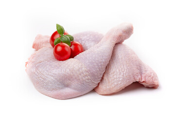 Raw chicken thighs with skin decorated with tomatoes and basil on a white background.