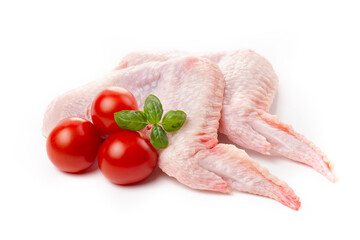 Raw chicken wings with skin decorated with tomatoes and basil on a white background.
