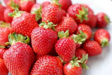 Fresh red strawberries with leaves on a white plate. Ripe strawberry for background
