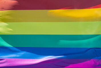 Rainbow flag in sunshine against blue sky
