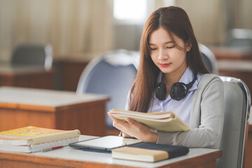 Fototapeta na wymiar Stock photo of a young Asian woman college student in student uniform reading book and studying in classroom