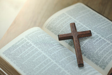A cross with the holy bible is placed on a wooden table on Sunday. worship prayer and bible study...