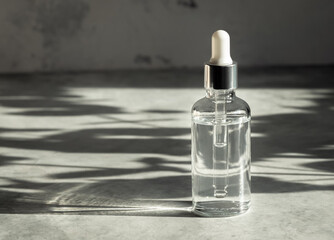Herbal oil in glass bottle with dropper pipette on grey background with shadows, free space for...