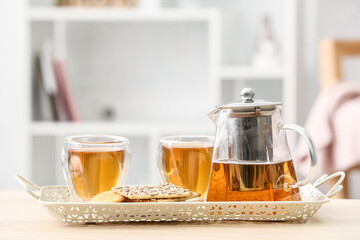 Tray with teapot, cookies and glasses of hot beverage on table