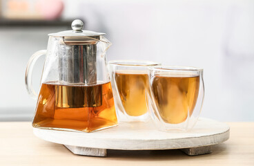 Teapot and glasses of hot beverage on table
