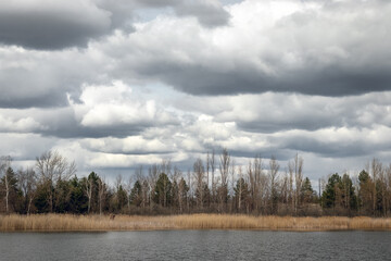 View of the river bay and forest in ghost town Pripyat, nature and dramatic cloudy sky in early spring in Chernobyl Exclusion Zone, Ukraine