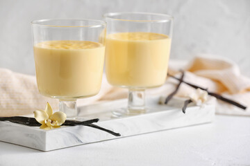 Board with tasty vanilla pudding on light background