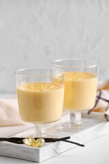 Board with tasty vanilla pudding on light background