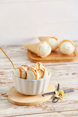 Ramekin with tasty vanilla ice cream on light wooden background