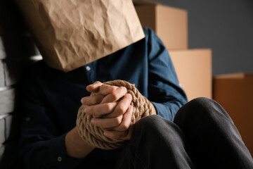 Male hostage with paper bag sitting on floor in room