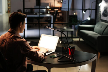 Young man using laptop at home late in evening