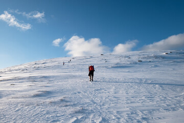 Man backpacker mountaineering on snow hill with blue sky at Lofoten Islands