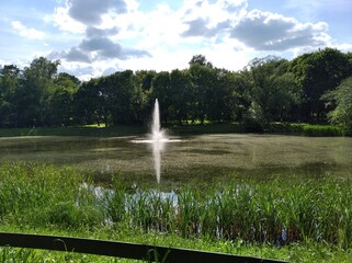 Olsztyn - Jakubowo - a pond with a fountain surrounded by trees.