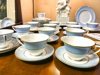 An identical  set of empty China tea cups on saucers laid out on a table 
