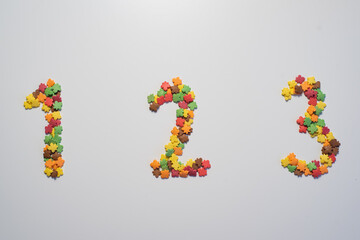 Numeral One hundred twenty three from sweet pastry topping in the form of colorful foliage on a white background.
