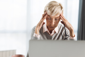  Senior businesswoman having a headache while working in an office