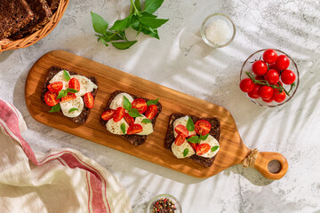 Whole wheat bread sandwiches with cheese, tomatoes and basil leaves. Healthy snack concept.