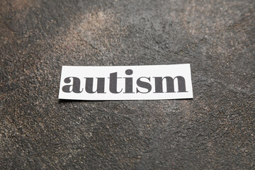 Piece of paper with word AUTISM on grunge background