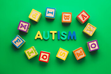 Word AUTISM and cubes on color background