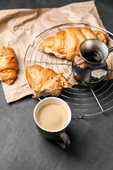 Pot, cup of coffee and croissant on dark background