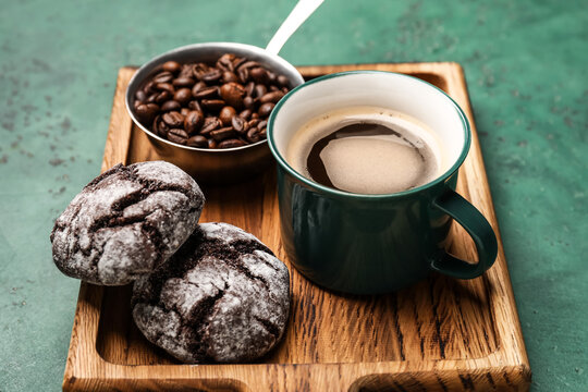 Cup of freshly brewed coffee and cookies on color background
