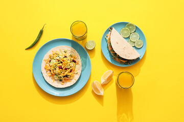 Plates with tasty tacos, lime and glasses of juice on color background