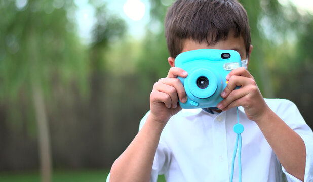 Boy taking a photo with an instant camera in a garden. Selective focus. Copy space. No face.