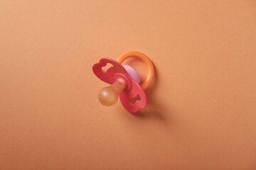 Baby pacifier on an orange background, top view, place for an inscription