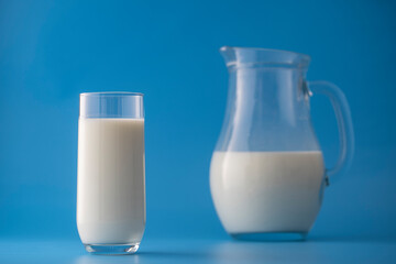 White milk in a jug and glass on a blue background. Dairy product concept
