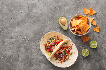 Plate with tasty tacos and nachos on grunge background