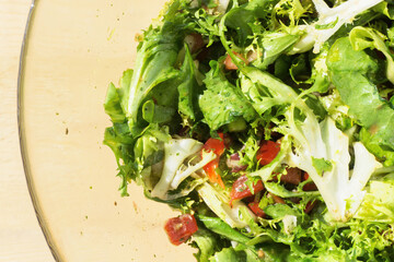 Healthy green salad background. Fit dinner texture. Raw vegetables mix. Closeup salad in glass bowl. Wooden table summer lunch background.