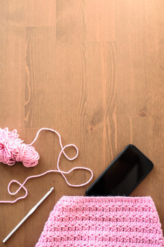 Online courses on learning to crochet. Top view of a pink ball of yarn with a crochet hook, phone screen for remote learning to knit a star pattern. Copying a space.