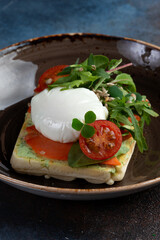 sandwich with poached egg, salmon and tomatoes in a plate.