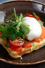 sandwich with poached egg, salmon and tomatoes in a plate.