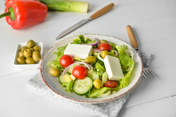 Plate with fresh salad on light wooden background