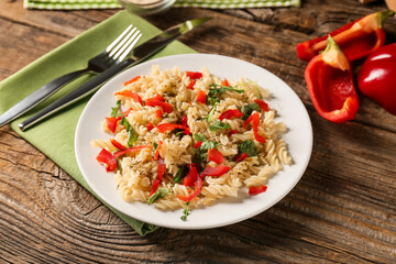 Plate with tasty pasta and bell pepper on wooden background