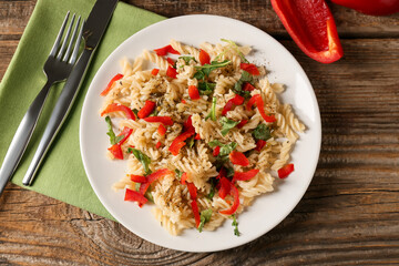 Plate with tasty pasta and bell pepper on wooden background
