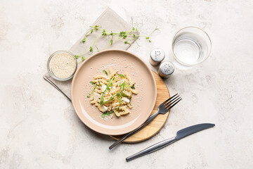 Plate with tasty pasta and glass of water on light background