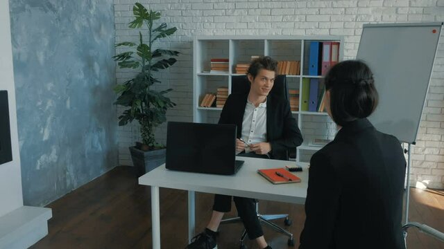 A young girl is interviewed for a new job in the office. A young CEO is interviewing a beautiful attractive girl for the position of a new employee of the company.