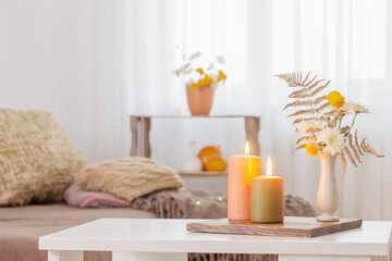 burning candles with autumn decor on white table at home - obrazy, fototapety, plakaty
