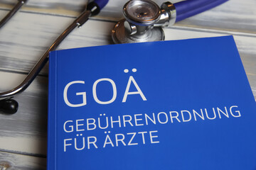 Viersen, Germany - May 9. 2021: Closeup of isolated book with stethoscope about german doctors scale of fees (Gebuhrenordnung, goa) for private insurance (focus on center of upper lettering) - obrazy, fototapety, plakaty
