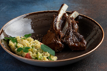 Lamb rack in a plate on a dark background.